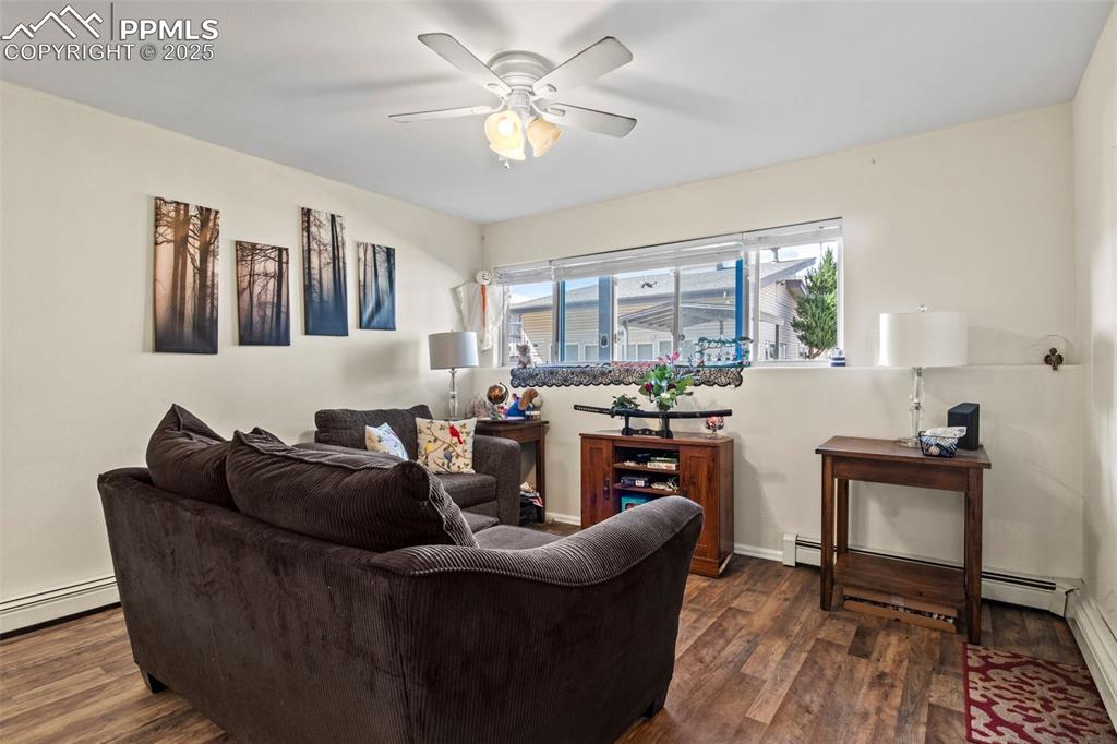 Image 3 of 21: Living room featuring dark wood-type flooring, a ceiling fan, and a baseboa