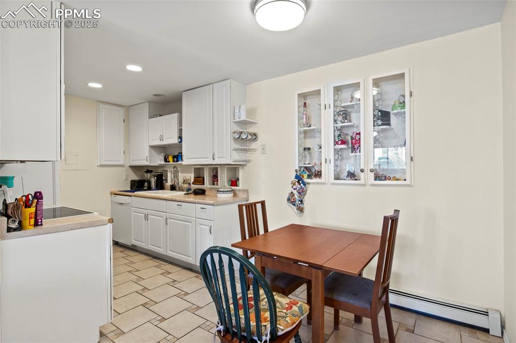 Image 7 of 21: Kitchen with a baseboard heating unit, white cabinets, recessed lighting, o