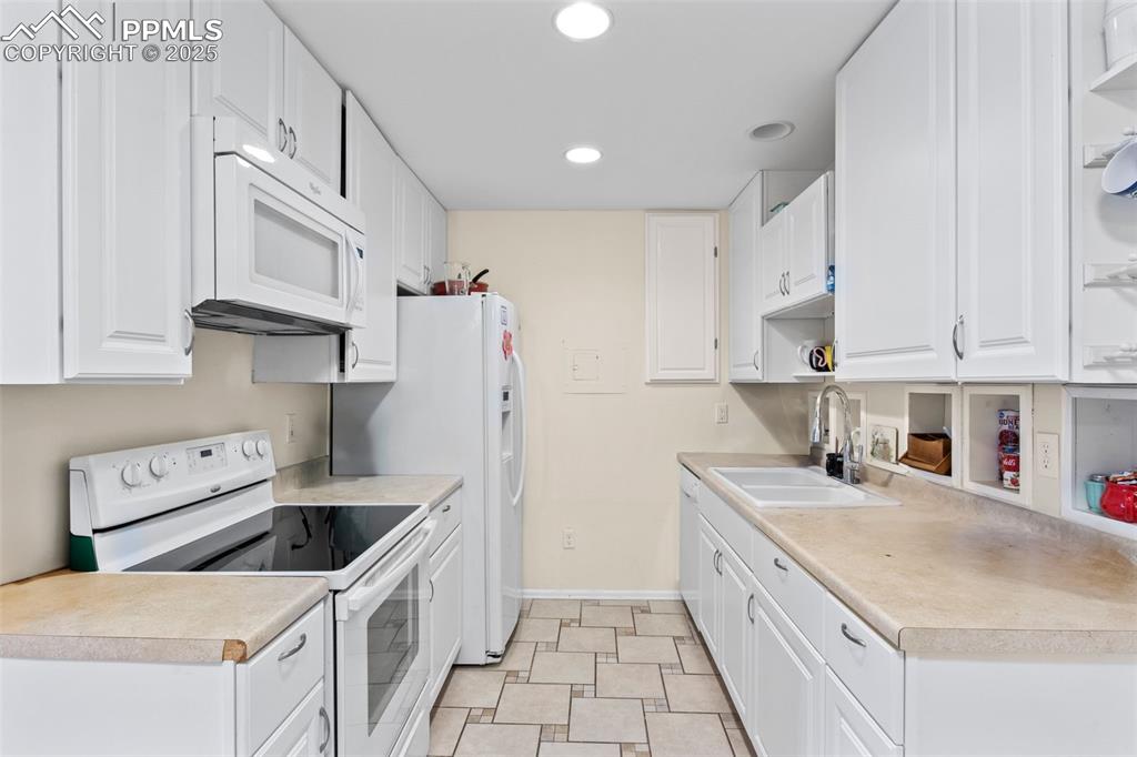 Image 9 of 21: Kitchen featuring white appliances, white cabinetry, light countertops, ope