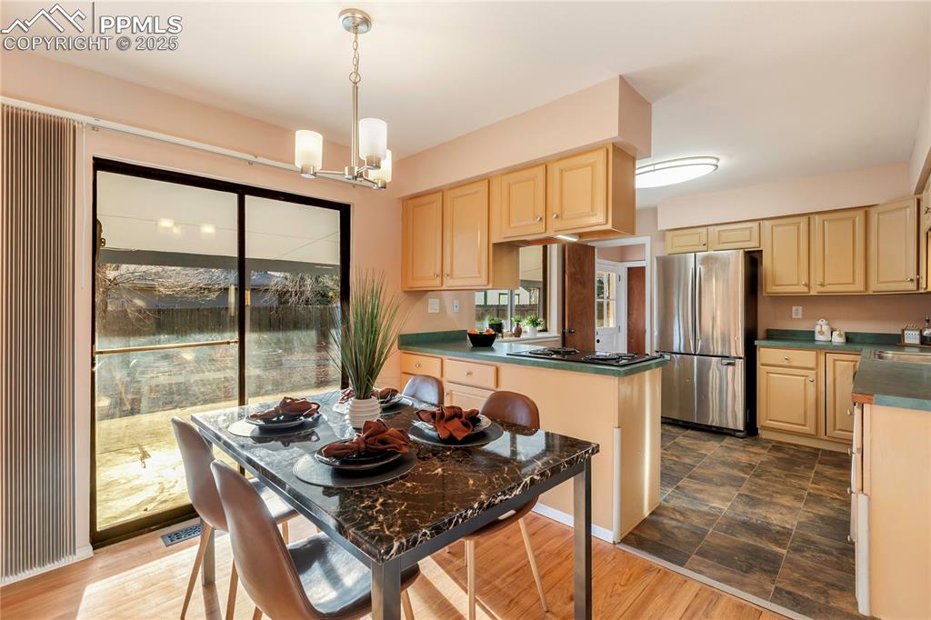 Image 14 of 38: Eat-in kitchen features updated light fixtures and stainless steel applianc