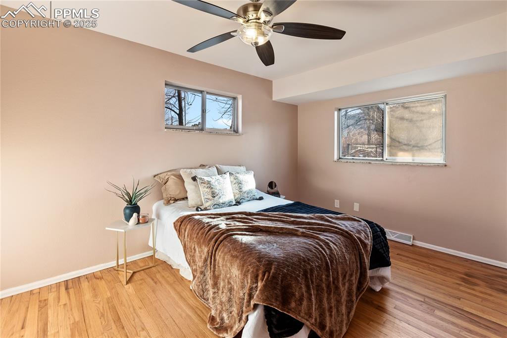 Image 19 of 38: Spacious primary bedroom on main level with refinished hardwood flooring an