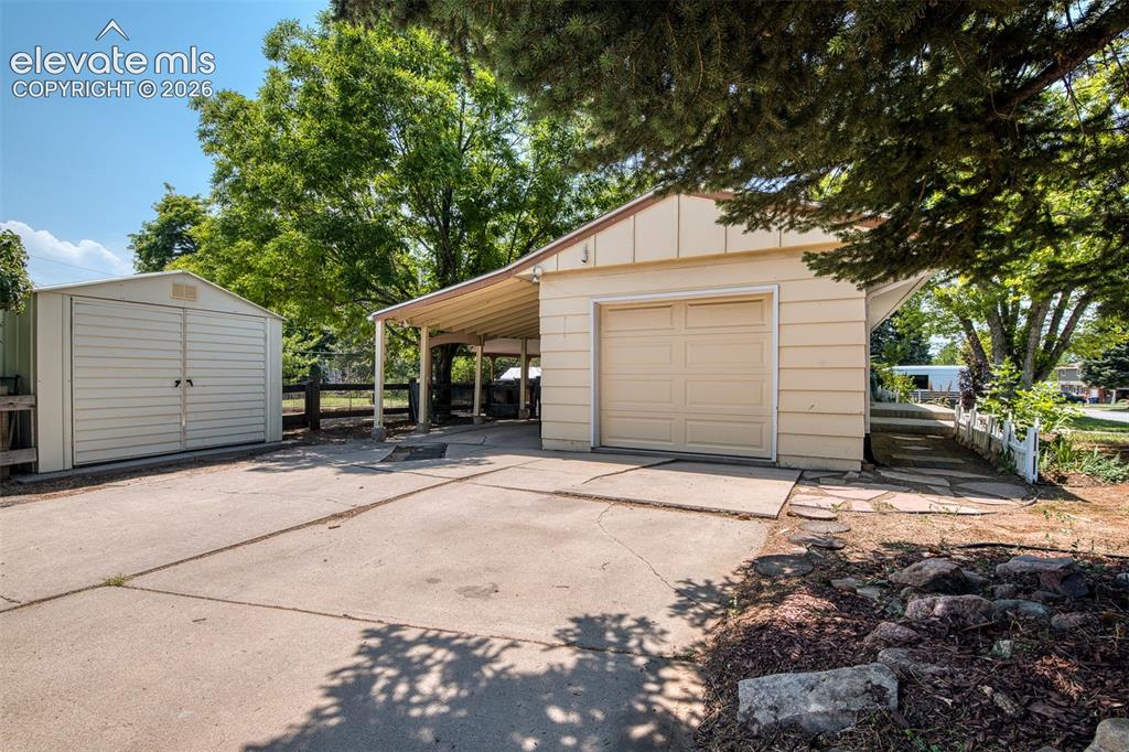 Image 4 of 40: Wide driveway with 1 car garage and covered carport.