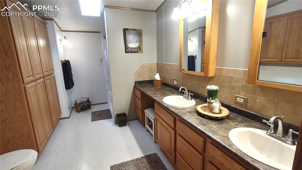 Image 19 of 42: Primary bath has double sink & mirrors plus tons of custom cabinetry.