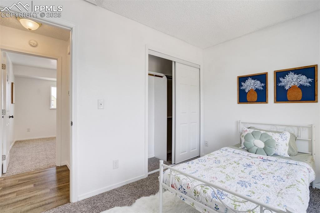 Image 18 of 33: Carpeted bedroom with a textured ceiling, a closet, and wood finished floor