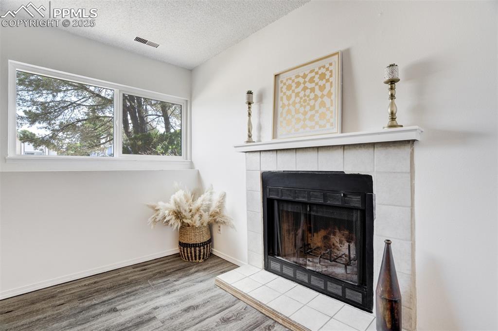 Image 22 of 33: Detailed view of a textured ceiling, wood finished floors, and a tiled fire
