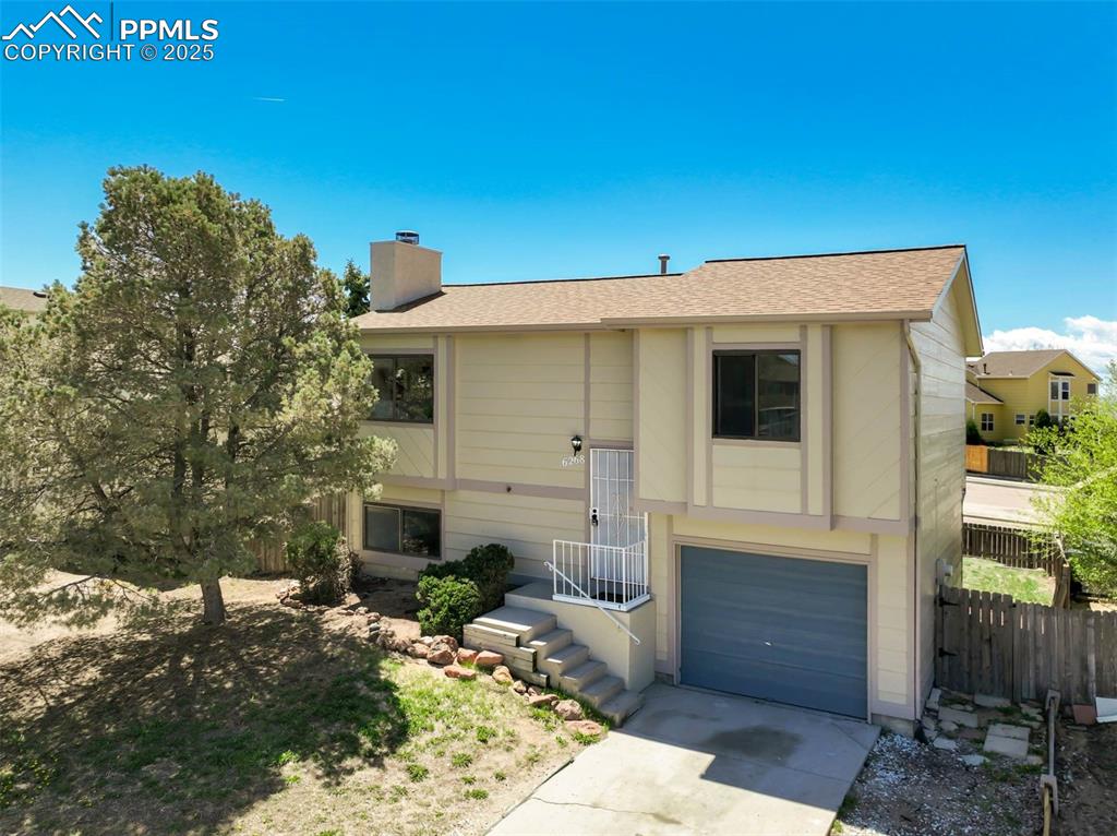 Image 32 of 33: View of front of property with a chimney, a garage, fence, concrete drivewa