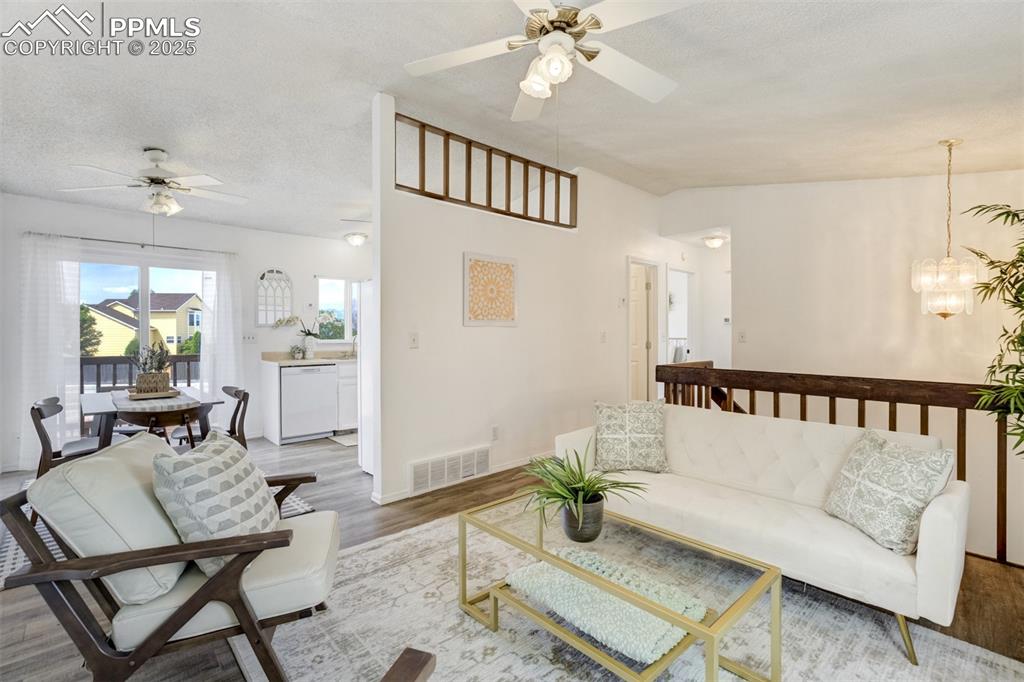 Image 5 of 33: Living room featuring ceiling fan, wood finished floors, a chandelier, vaul