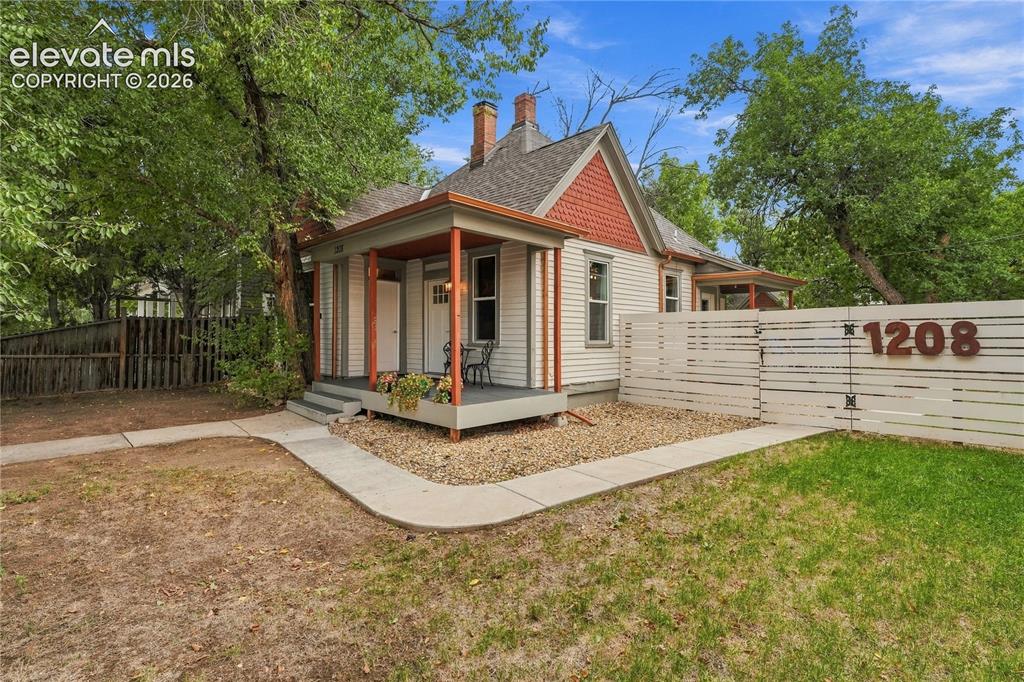 Image 2 of 50: Front of Main Home with inviting covered porch and fully fenced front yard.