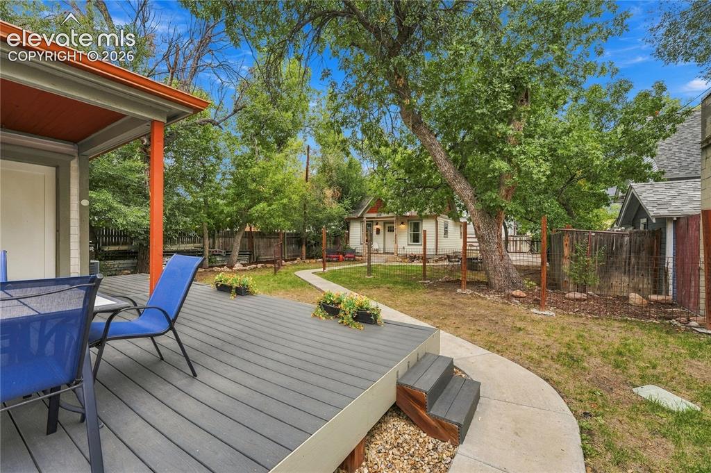 Image 27 of 50: Deck and covered porch on the primary house. View to the second home and ba