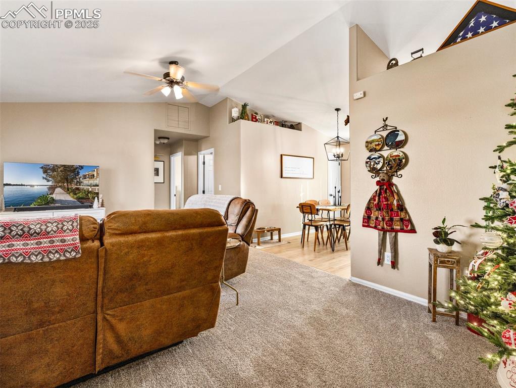 Image 10 of 41: Living area featuring light carpet, high vaulted ceiling, and a ceiling fan