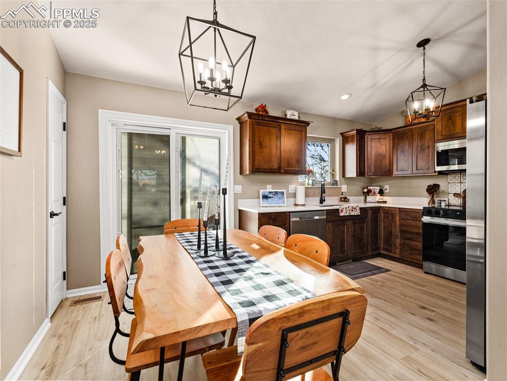Image 13 of 41: Kitchen featuring light countertops, a chandelier, dark brown cabinets, sta