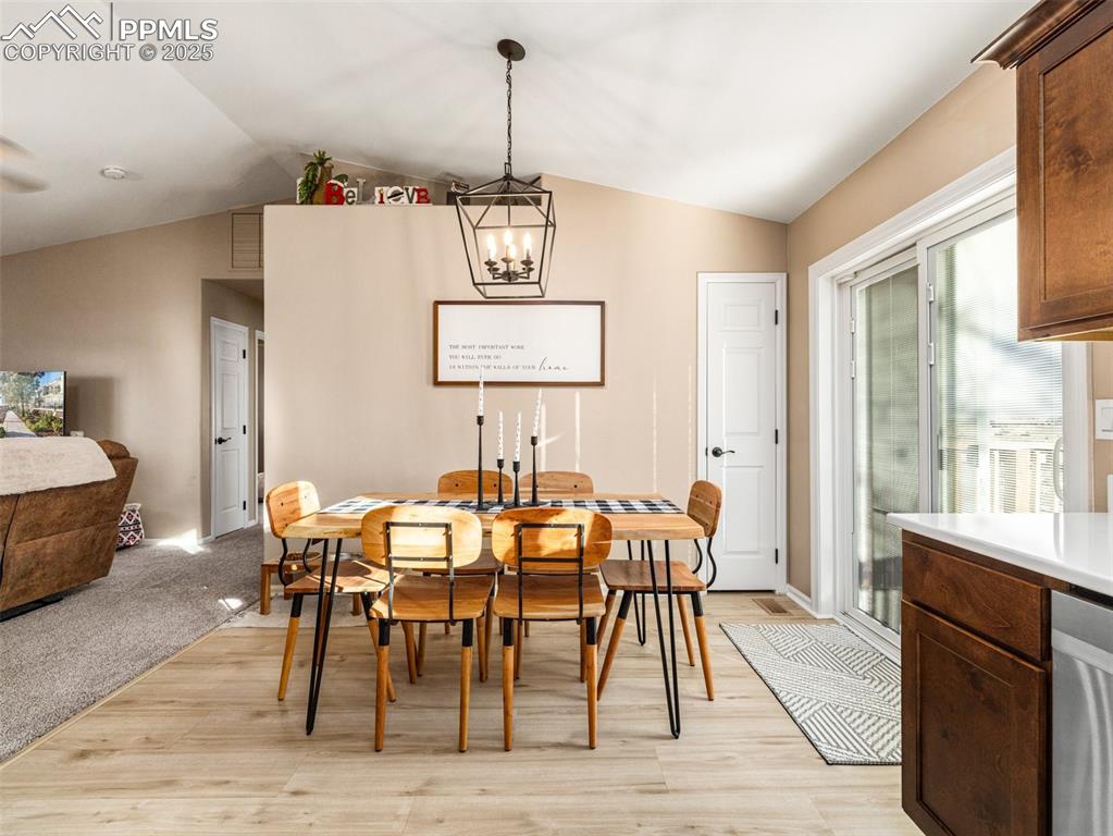 Image 14 of 41: Dining space with vaulted ceiling, a chandelier, and light wood-style floor