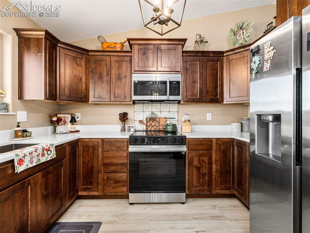 Image 15 of 41: Kitchen featuring appliances with stainless steel finishes, dark brown cabi