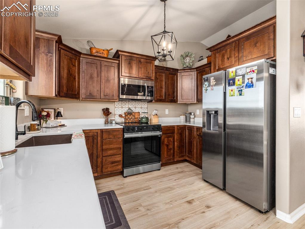 Image 16 of 41: Kitchen with appliances with stainless steel finishes, lofted ceiling, pend