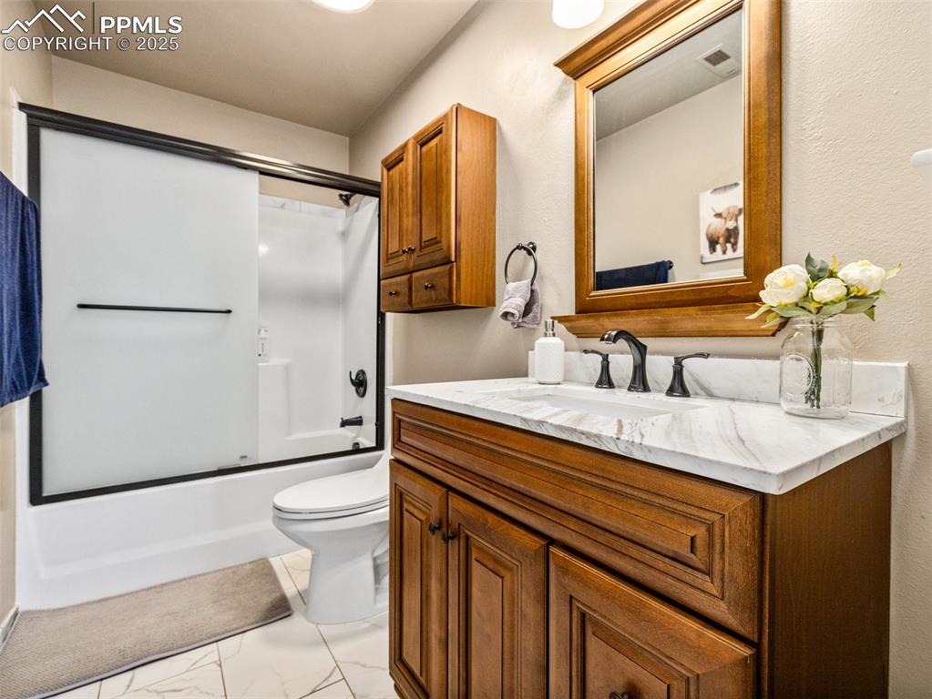 Image 28 of 41: Full bathroom with vanity, combined bath / shower with glass door, and ligh