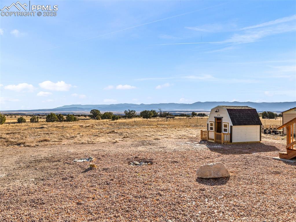 Image 36 of 41: View of yard featuring a mountain view, a storage unit, and a rural view
