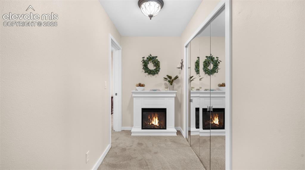 Image 10 of 37: Hallway featuring a built-in electric fireplace with a white mantel, mirror