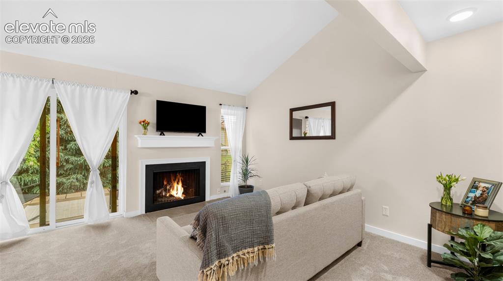Image 13 of 37: Living area featuring a fireplace with a white mantel, mounted television,