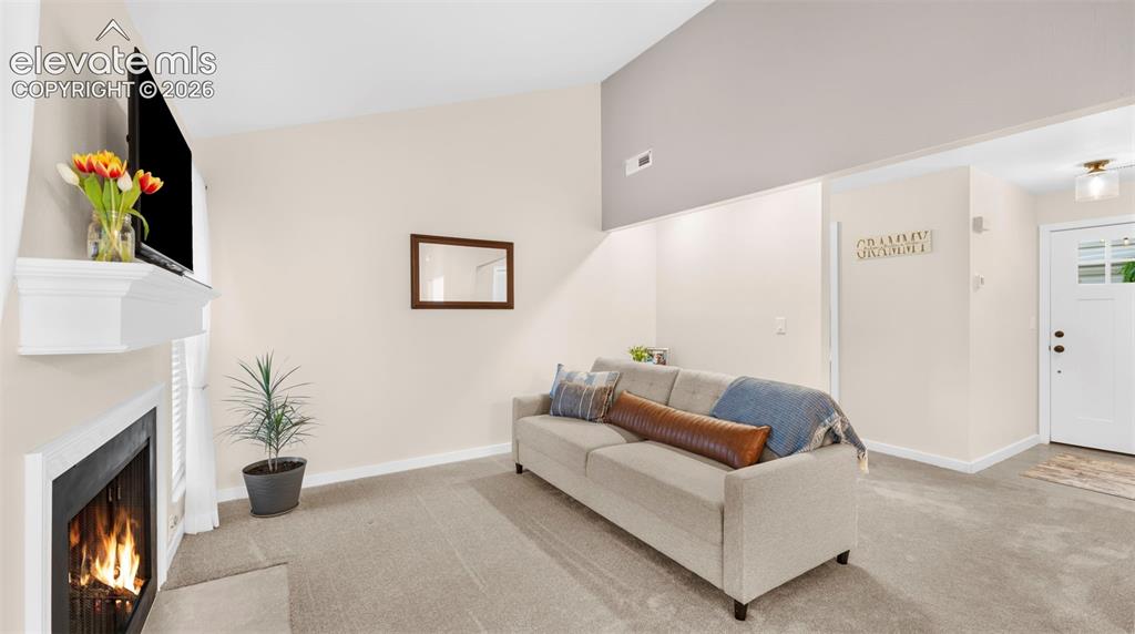 Image 14 of 37: Living area featuring a fireplace with a white mantel, neutral wall paint,