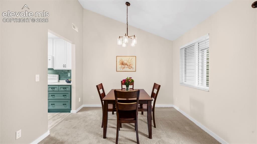 Image 15 of 37: Dining area featuring vaulted ceilings, a contemporary chandelier, and a wi