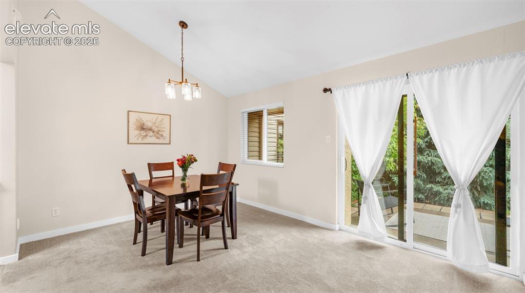 Image 16 of 37: Dining area featuring vaulted ceilings, a contemporary chandelier, neutral