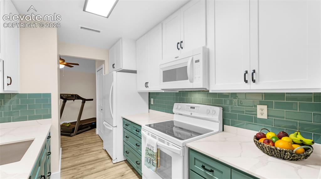 Image 18 of 37: Contemporary kitchen featuring white upper cabinetry, teal lower cabinetry,