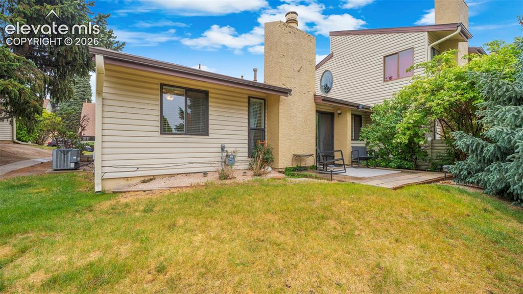 Image 23 of 37: Rear property exterior with beige siding and two prominent stucco chimneys