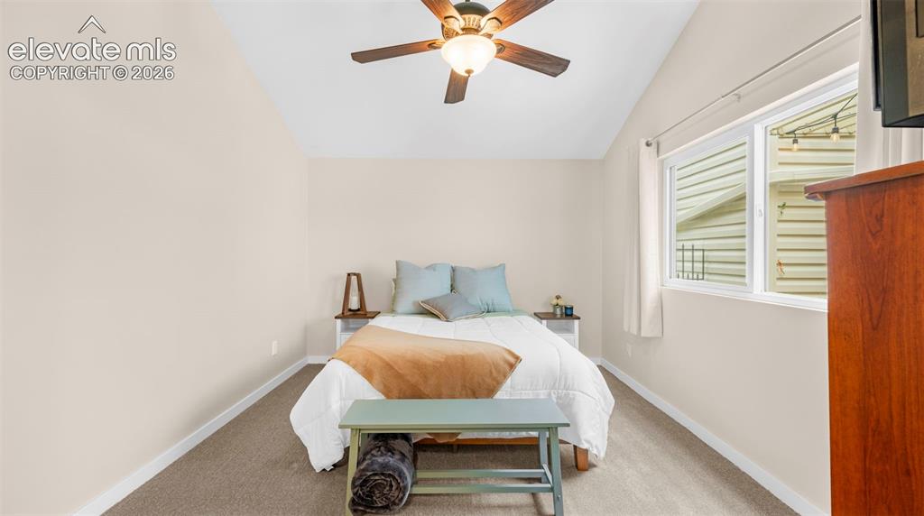 Image 8 of 37: Bright room featuring a vaulted ceiling with a ceiling fan, carpeted floori