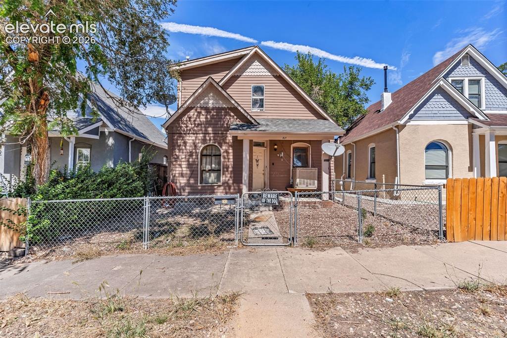 Image 1 of 3: Exterior features include a chain-link fence, a front porch, and a gable ro
