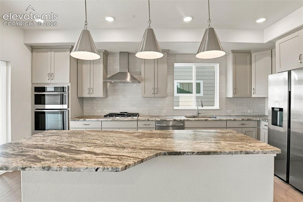 Image 10 of 50: Kitchen featuring stone-finish countertops, stainless steel appliances, lig