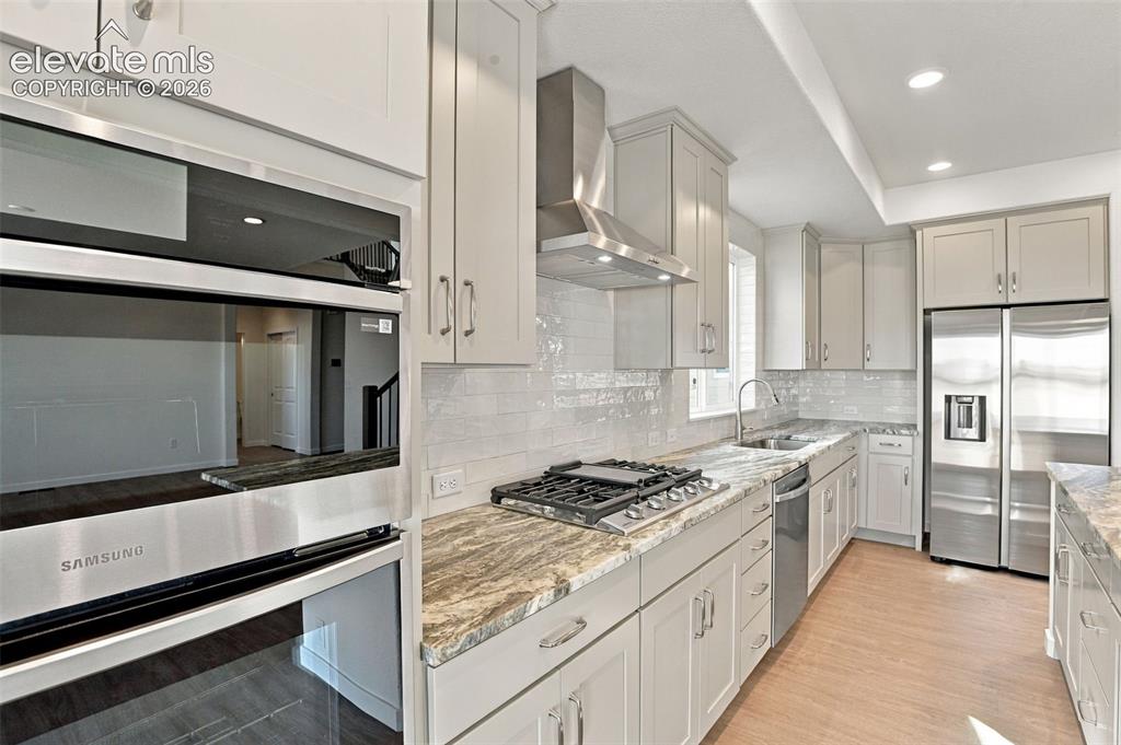 Image 12 of 50: Kitchen featuring shaker-style cabinetry, patterned stone-surface counterto