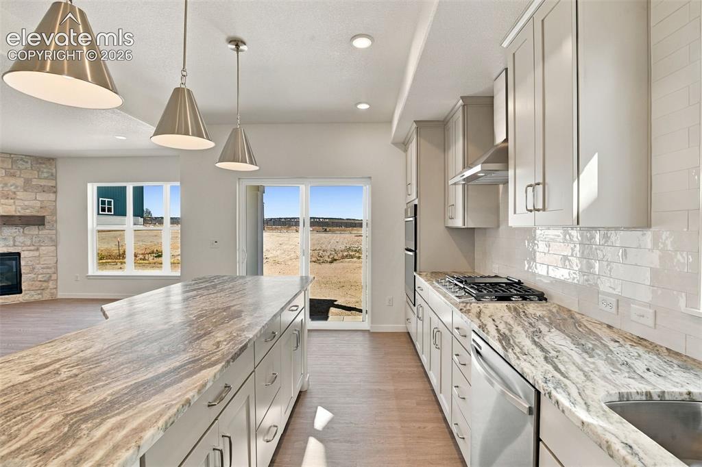Image 13 of 50: Kitchen featuring custom cabinetry, stone countertops, stainless steel appl