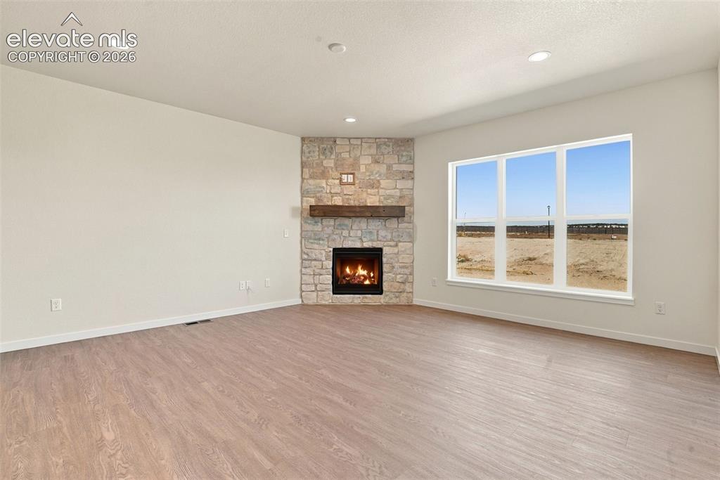 Image 15 of 50: Corner fireplace with stone masonry surround, wood-finish mantel, and wood-