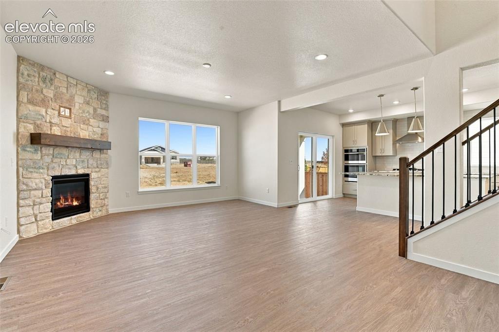 Image 16 of 50: Floor-to-ceiling stone fireplace with a wood mantel, wood-finish flooring, 