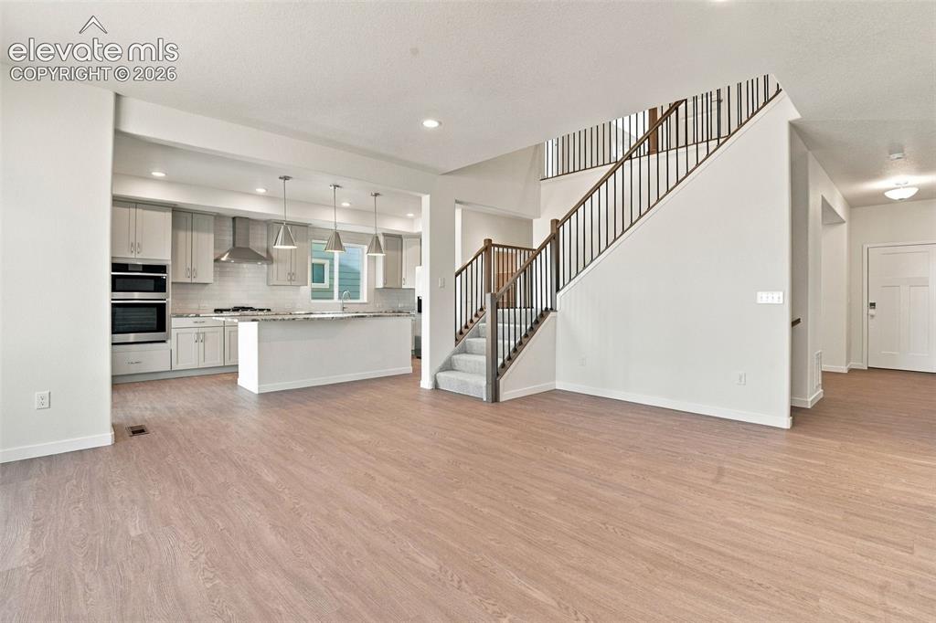 Image 18 of 50: Open-concept floor plan featuring wood-finish flooring, a kitchen with ston