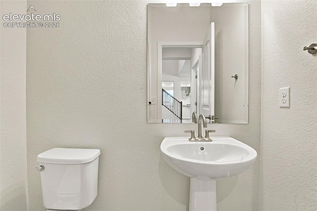 Image 22 of 50: Powder room featuring a white pedestal sink, dual-handle brushed nickel fau