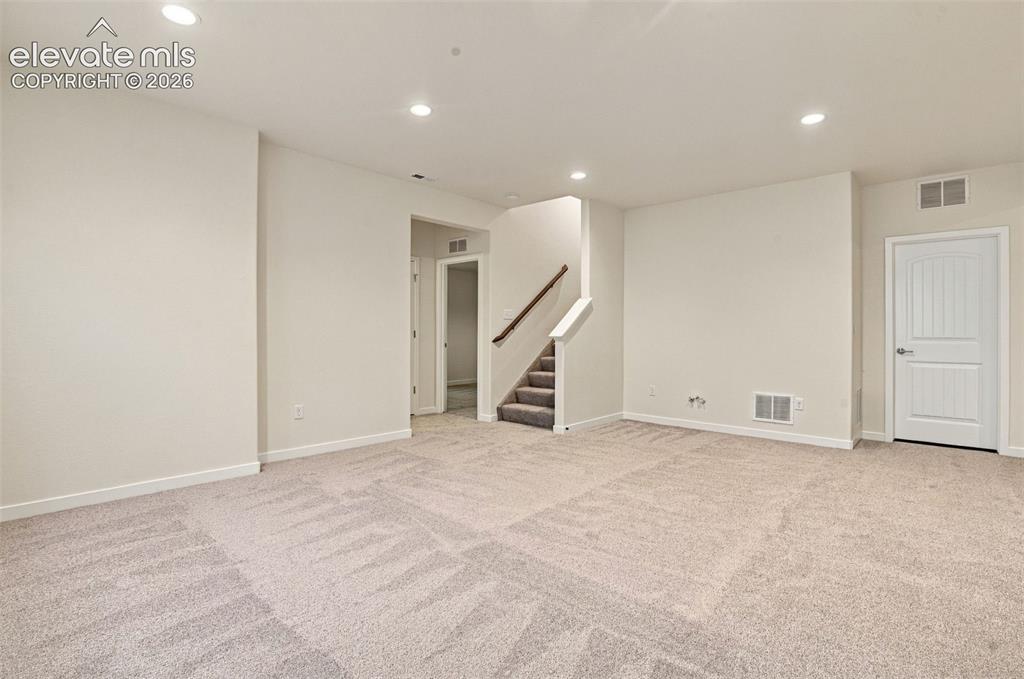 Image 38 of 50: Neutral-toned carpeted interior featuring recessed lighting, a staircase wi