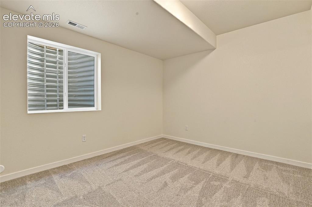 Image 39 of 50: Neutral-toned wall finish, wall-to-wall carpeting, and a corrugated metal w