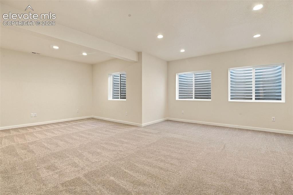 Image 41 of 50: Neutral-toned carpeted interior featuring recessed lighting and three egres