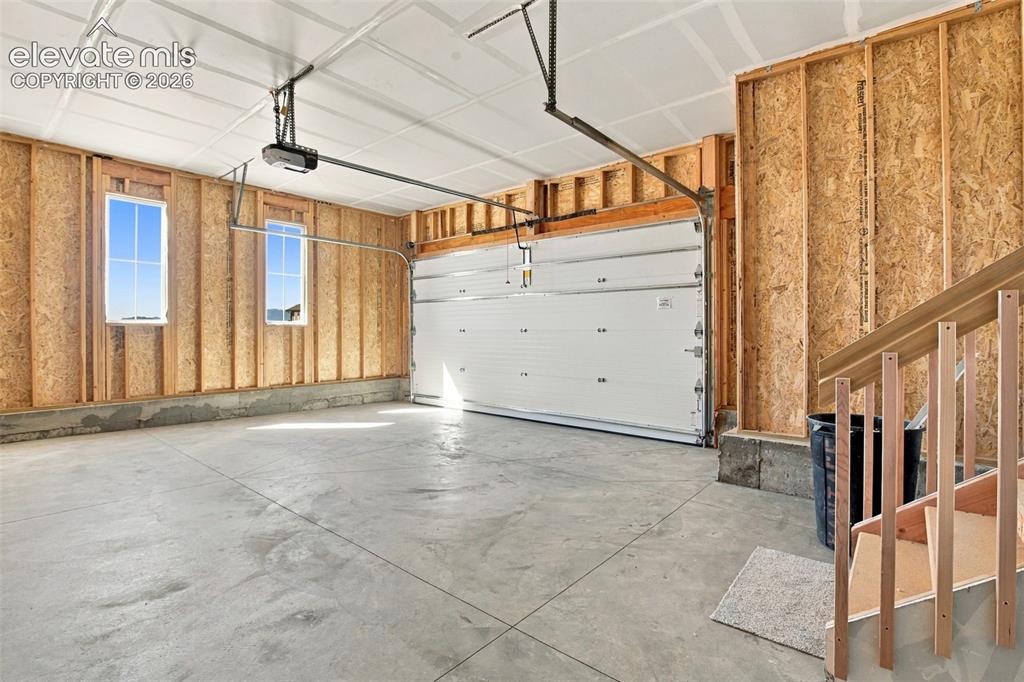 Image 45 of 50: Attached garage featuring exposed wood-stud walls, a concrete floor, two wi