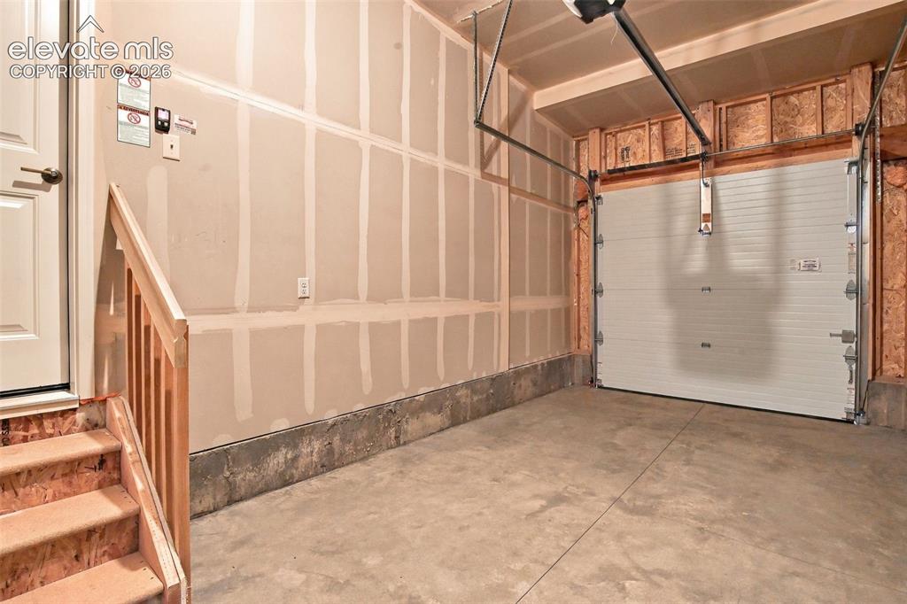 Image 47 of 50: Enclosed garage featuring a concrete floor, horizontal roll-up door, and wo