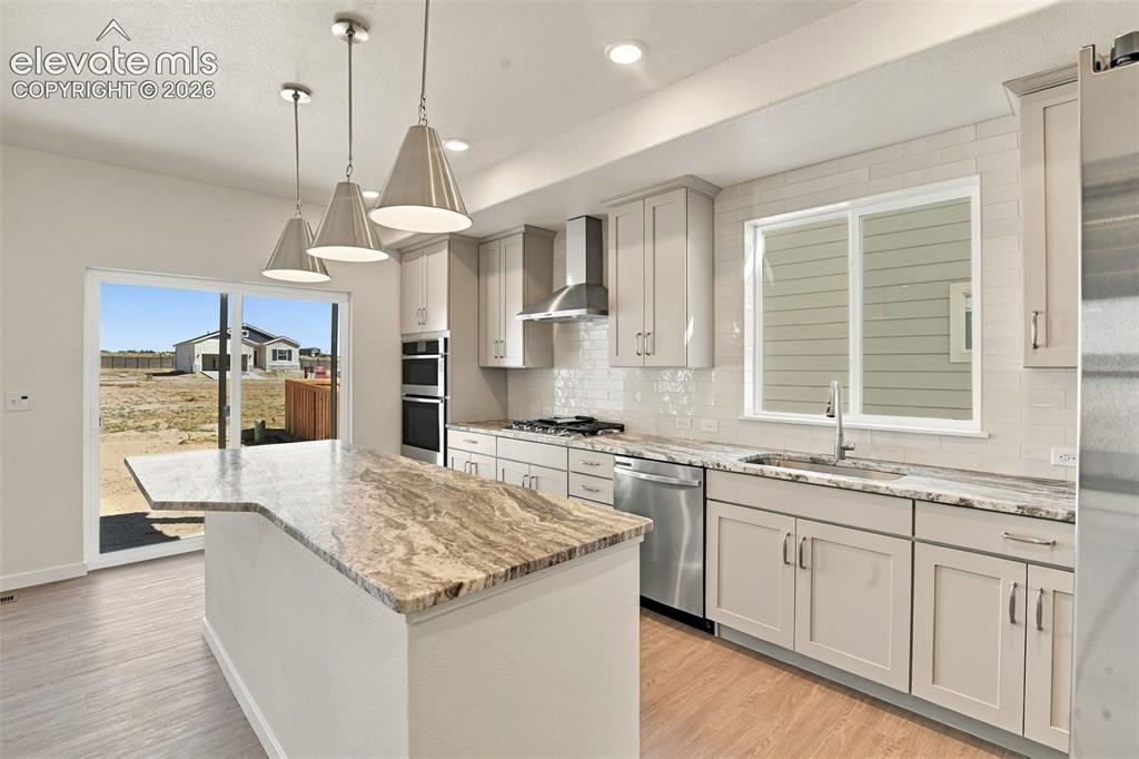 Image 7 of 50: Kitchen featuring stone countertops, an expansive center island, stainless