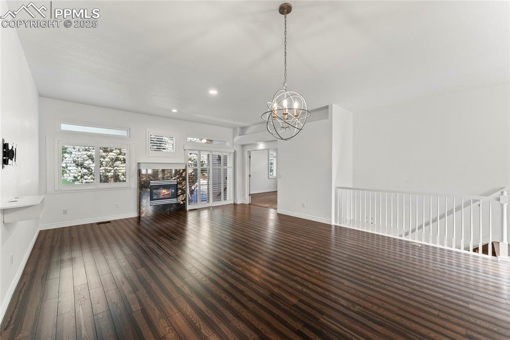 Image 10 of 50: Unfurnished living room featuring wood finished floors, a chandelier, a pre