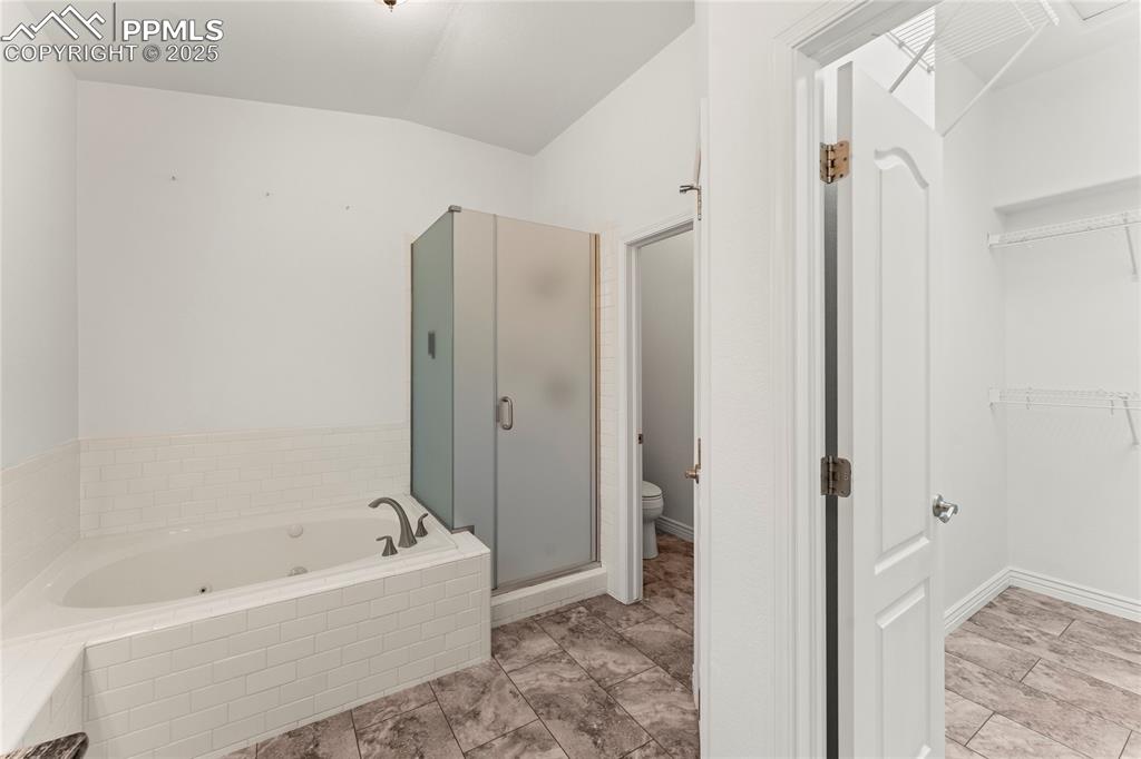 Image 21 of 50: Bathroom with a tub with jets, a shower stall, a spacious closet, and vault