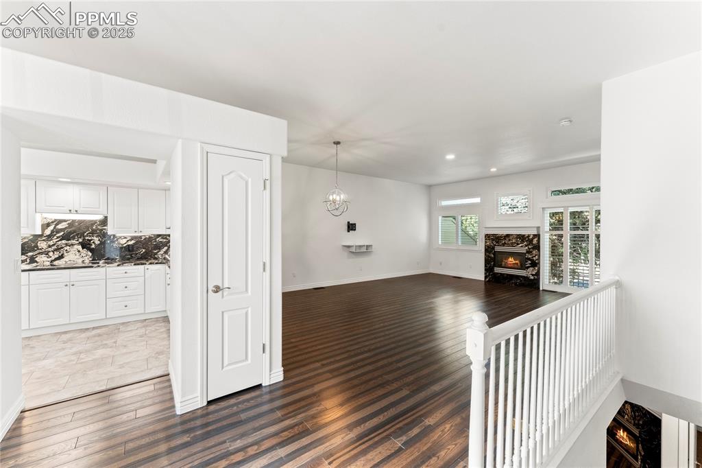 Image 23 of 50: Unfurnished living room featuring a premium fireplace, dark wood-style floo