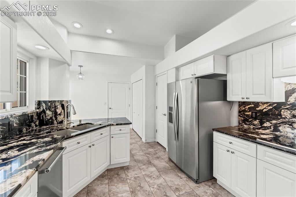 Image 24 of 50: Kitchen with stainless steel appliances tasteful backsplash, white cabinets