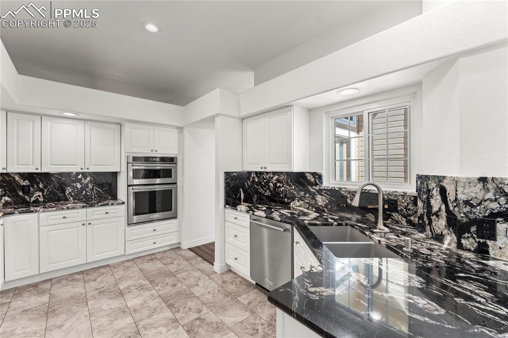 Image 26 of 50: Kitchen featuring stainless steel appliances, decorative backsplash, dark s