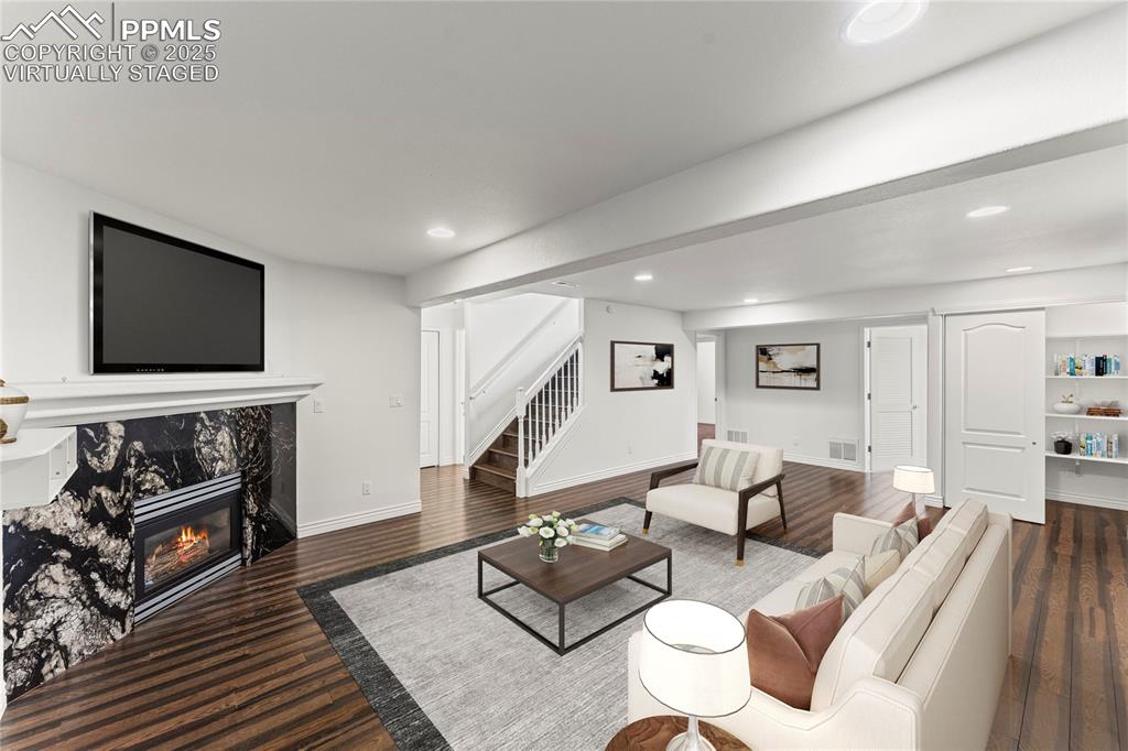 Image 32 of 50: Virtually staged living room with a fireplace, stairway, recessed lighting,