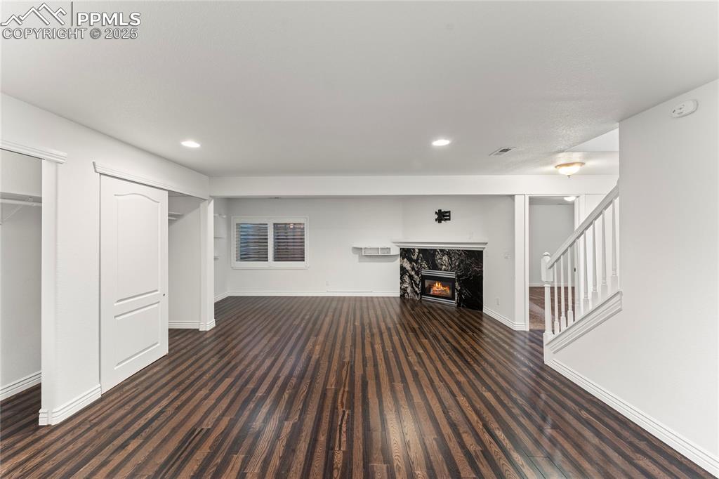 Image 45 of 50: Unfurnished living room featuring a premium fireplace, stairway, wood finis