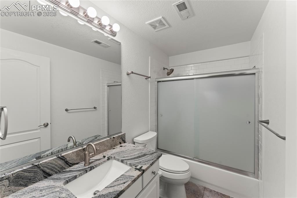 Image 46 of 50: Full bathroom with vanity, enclosed tub / shower combo, and tile patterned 